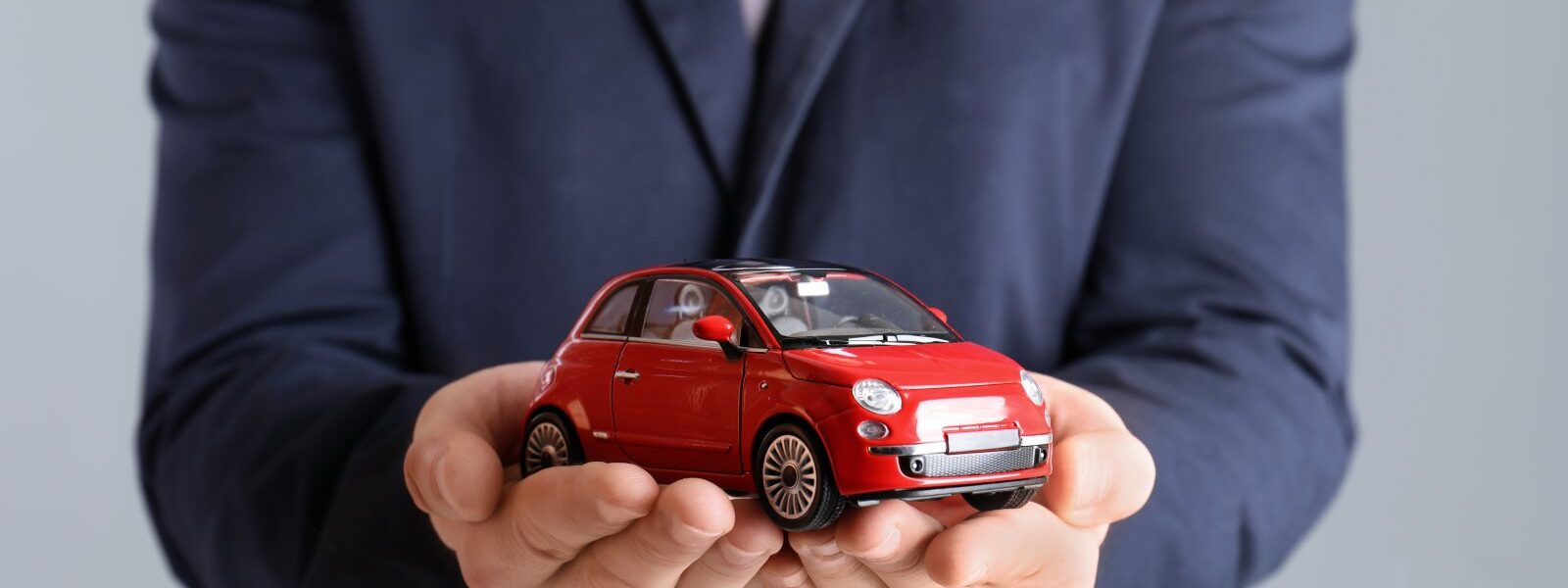 male insurance agent holding toy car on grey backg 2026 03 05 11 45 45 utc