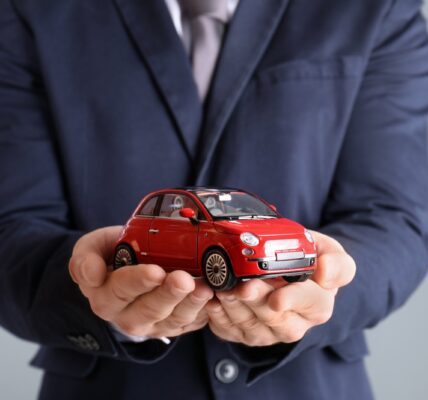 male insurance agent holding toy car on grey backg 2026 03 05 11 45 45 utc