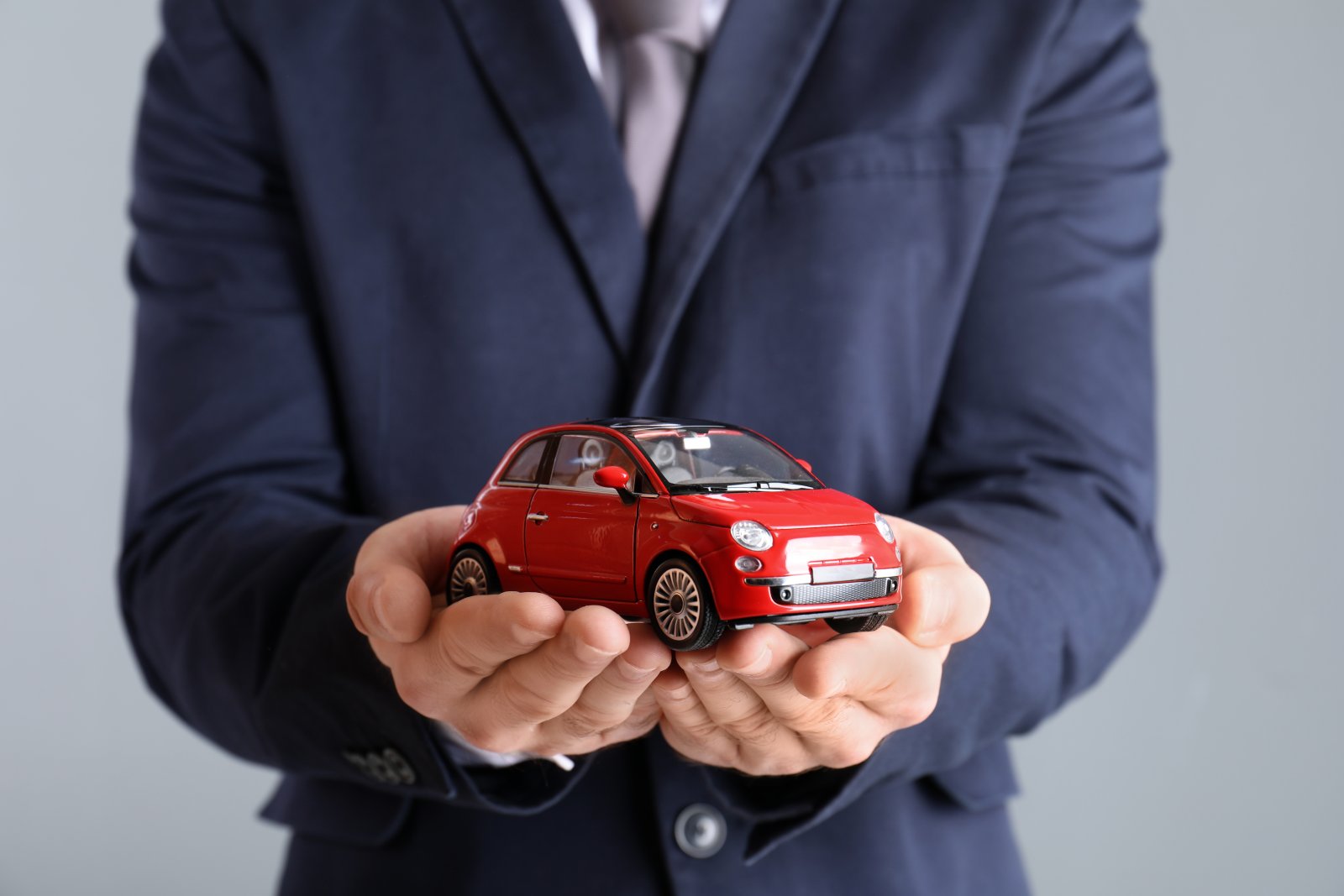 male insurance agent holding toy car on grey backg 2026 03 05 11 45 45 utc